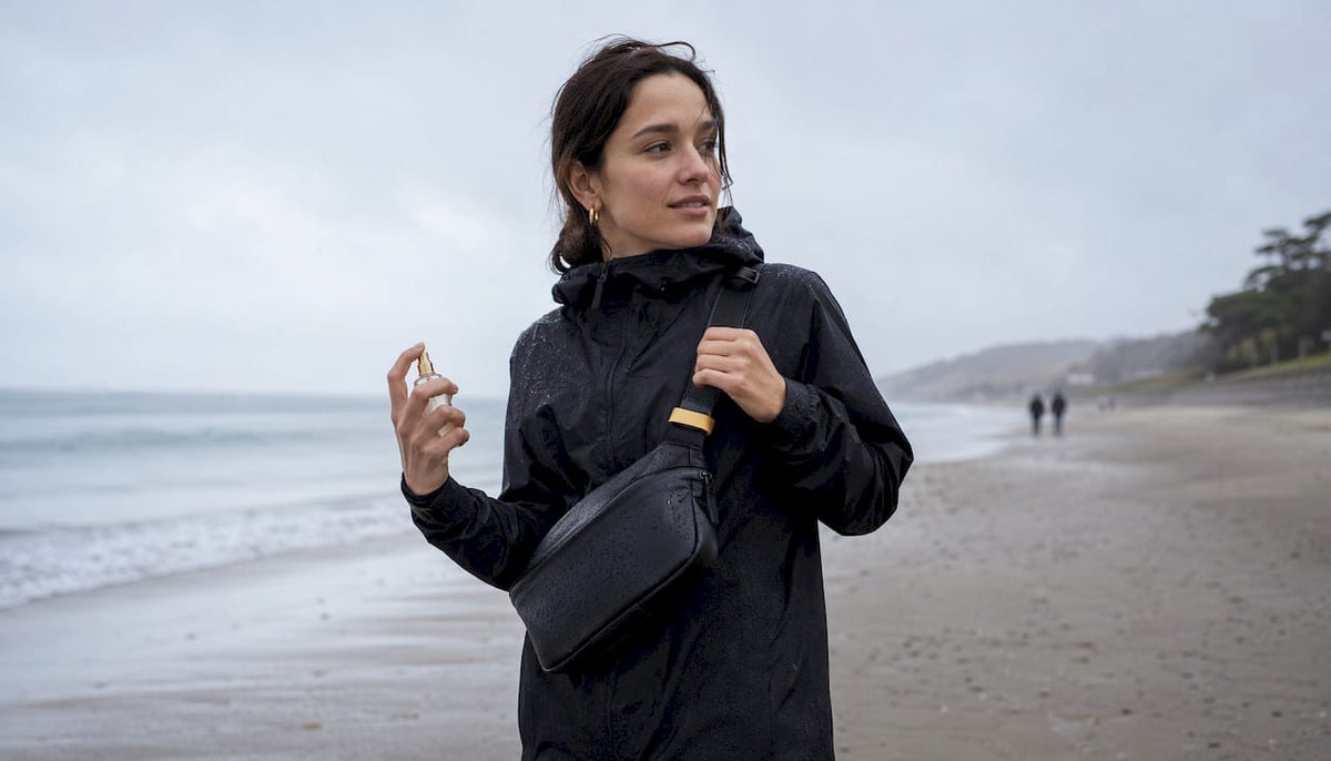 Woman wearing waterproof sling bag holding perfume atomizer