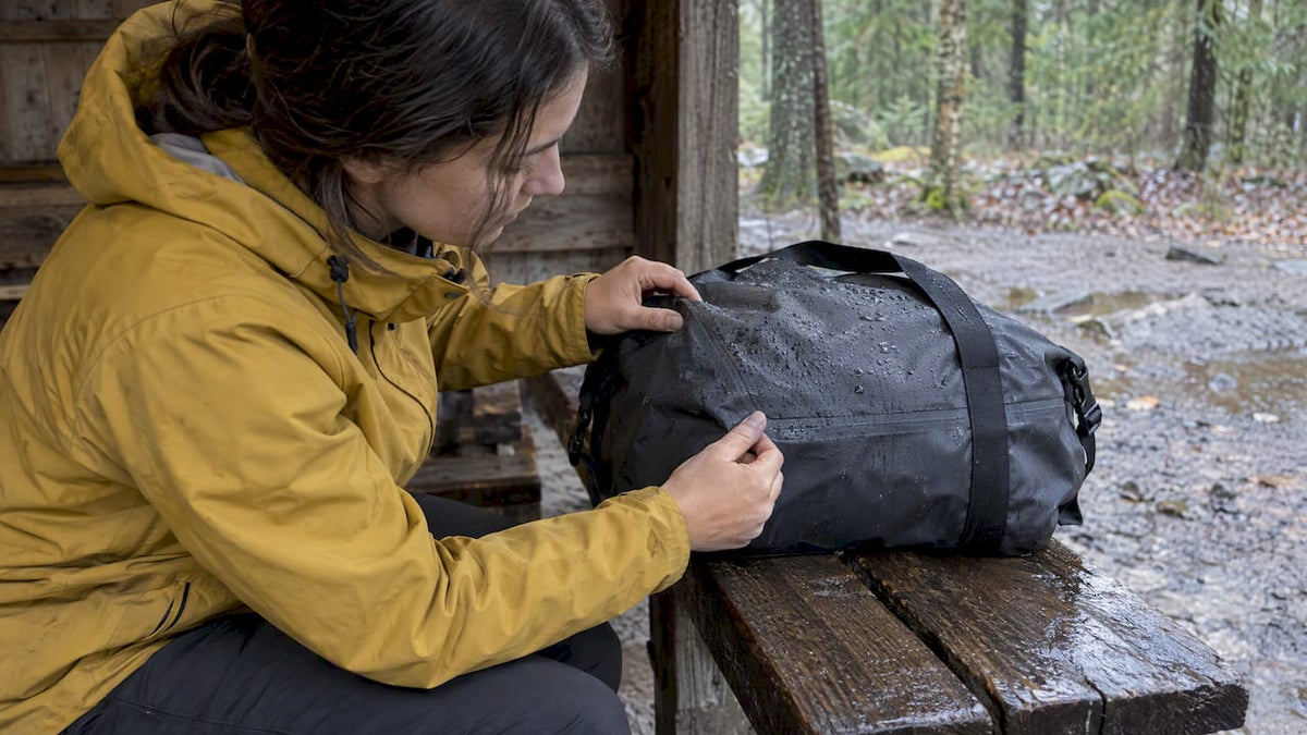 Traveler inspecting seams on a wet travel bag