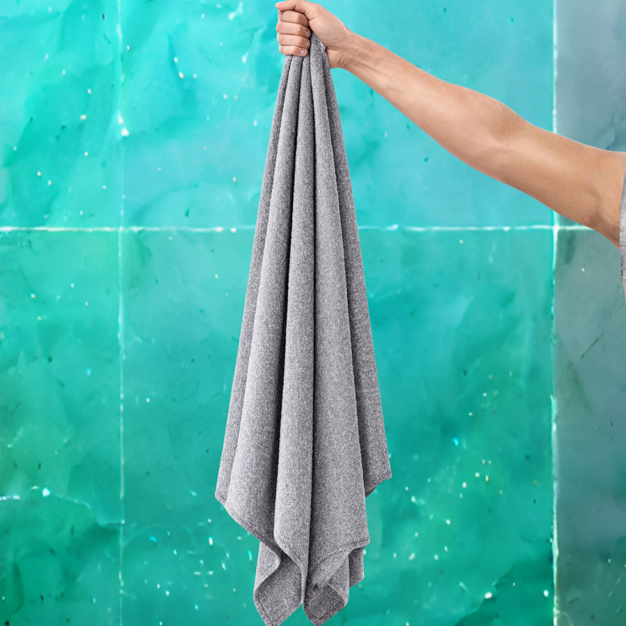 Gray towel held by a hand against a teal tiled wall background